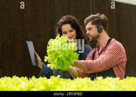 Due piccoli imprenditori proprietari di orti biologici stanno attualmente presentando i clienti e mostrando loro il suo g di verdure biologiche Foto Stock