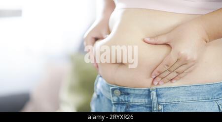 Donna obesa con grasso agitato per la pancia. Donna in sovrappeso che tocca la pancia grassa e vuole perdere peso. Donna grassa con tigh Foto Stock