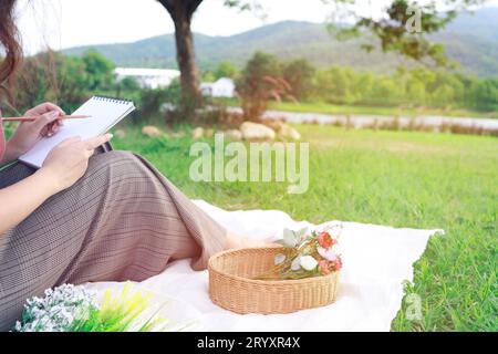 Donna sola che riposa in un picnic nel parco naturale all'aperto durante una giornata di sole, godendosi l'estate e sognando Foto Stock