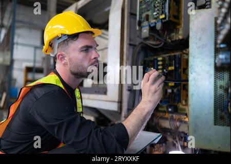 Il tecnico ispeziona l'impianto elettrico e ripara il sistema meccanico nell'armadio di controllo della macchina. in ordine per la m Foto Stock