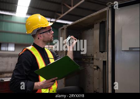 Il tecnico ispeziona l'impianto elettrico e ripara il sistema meccanico nell'armadio di controllo della macchina. in ordine per la m Foto Stock