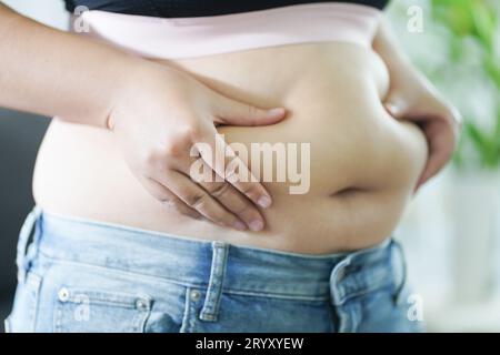 Donna obesa con grasso agitato per la pancia. Donna in sovrappeso che tocca la pancia grassa e vuole perdere peso. Donna grassa con tigh Foto Stock