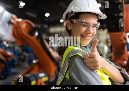 Ritratto di una donna ingegnere con la missione di controllare, testare, migliorare il software e calibrare il braccio robotico. Foto Stock