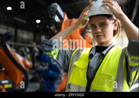 Ritratto di una donna ingegnere con la missione di controllare, testare, migliorare il software e calibrare il braccio robotico. Foto Stock