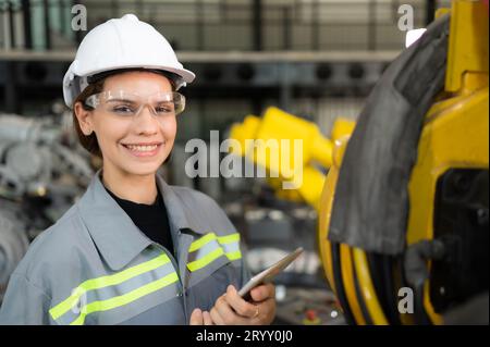 Un ingegnere donna installa un programma su un braccio robotico in un magazzino robot. E provare il funzionamento prima di inviare la macchina Foto Stock