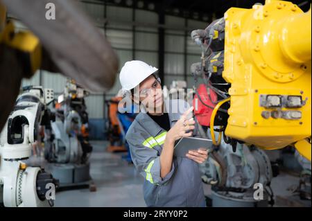 Un ingegnere donna installa un programma su un braccio robotico in un magazzino robot. E provare il funzionamento prima di inviare la macchina Foto Stock