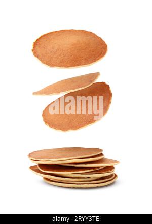 Molti gustosi pancake freschi che cadono su sfondo bianco Foto Stock