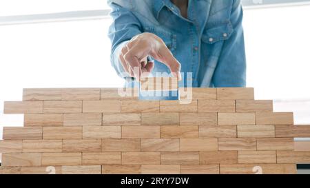 Gruppo di amici che giocano blocchi di legno gameÂ sul tavolo piegato puzzle tenendo blocchi di legno gioco pianificazione rischio e strategia in autobus Foto Stock