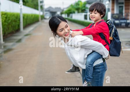 Mamma single che porta e gioca con i suoi figli vicino a casa con lo sfondo della villa. Concetto di persone e stili di vita. Felice f Foto Stock