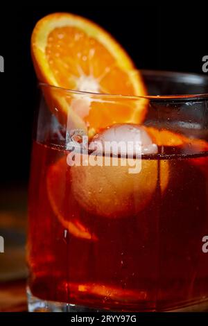 Cocktail alcolico Negroni o cocktail analcolico, bevanda con ghiaccio e scorza d'arancia come decorazione su tavolo di legno Foto Stock