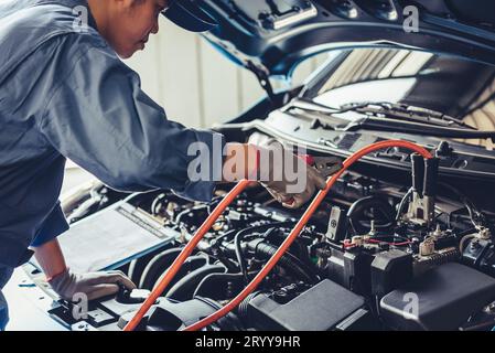 Autofficine fermo batteria energia elettrica attraverso i cavi ponticello e controllo al veicolo di manutenzione da parte del cliente secondo la rivendicazione ordine nel negozio di riparazioni auto in garage. Foto Stock