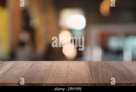 Tavolo vuoto di legno scuro davanti allo sfondo astratto di bokeh sfocato del ristorante. può essere utilizzato per la visualizzazione o il montaggio del pr Foto Stock