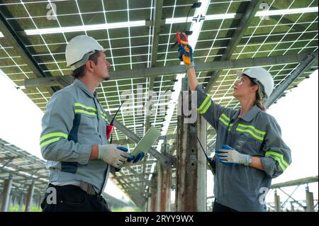 Un team di ingegneri elettrici sta ispezionando e manutenendo i pannelli solari in un sito di pannelli solari nel mezzo di cento acri Foto Stock