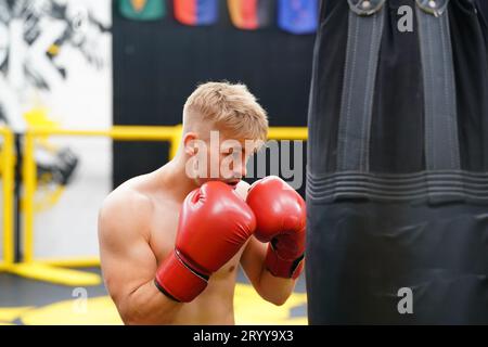 Muay Thai, l'arte marziale della Thailandia, Boxer che pratica il pugno con un sacco per costruire potenti pugni e muscoli. Foto Stock