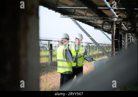 Un team di ingegneri elettrici sta ispezionando e manutenendo i pannelli solari in un sito di pannelli solari nel mezzo di cento acri Foto Stock