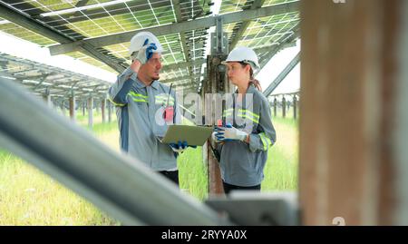 Un team di ingegneri elettrici sta ispezionando e manutenendo i pannelli solari in un sito di pannelli solari nel mezzo di cento acri Foto Stock