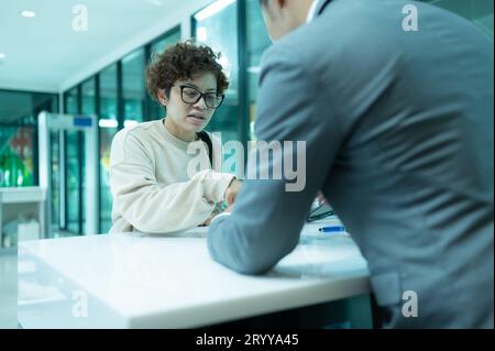 Il personale di terra della compagnia aerea aiuta i passeggeri a controllare i biglietti e i passaporti per il viaggio. Foto Stock