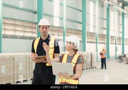 Incontro tra designer e responsabile del magazzino per organizzare la disposizione degli scaffali dei prodotti in un enorme magazzino vuoto. Foto Stock