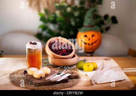 Biscotto al cioccolato con posate su un tagliere, servito con spugna di mela, more rosse, mandarini e una lanterna di jack nel bac Foto Stock