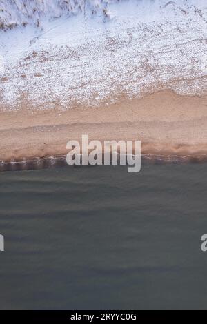 Inverno nella fredda spiaggia innevata del Mar Baltico a Danzica. Vista aerea della spiaggia innevata e delle dune e del paesaggio naturale scuro e calmo Foto Stock