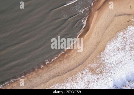 Inverno nella fredda spiaggia innevata del Mar Baltico a Danzica. Vista aerea della spiaggia innevata e delle dune e del paesaggio naturale scuro e calmo Foto Stock