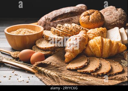 Diversi tipi di pane con cereali integrali nutrizionali su fondo di legno. Cibo e panificio in cucina. Colazione deliziosa Foto Stock