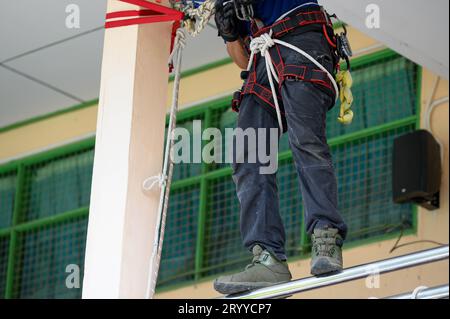 Primo piano dei vigili del fuoco addestramento della parte inferiore del corpo per esercitazioni antincendio dimostrando come uscire dall'edificio in fiamme con la fune di sicurezza c Foto Stock