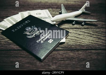 Vista dall'alto degli oggetti di scena e degli accessori di viaggio per l'organizzazione turistica con passaporto americano, aereo e banconote in dollari americani su Old W Foto Stock