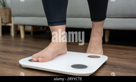 Piedi in piedi su bilance elettroniche per il controllo del peso. Strumento di misurazione in chilogrammi per il controllo della dieta Foto Stock