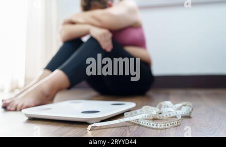 Donna obesa con agitazione grassa annoiata di dieta perdita di peso failÂ dieta grassa e scala donna asiatica triste su scala di peso a peso domestico Foto Stock