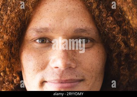 Ritratto di un felice uomo birazziale con capelli rossi ricci e lentiggini sorridenti Foto Stock