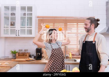 Padre e madre nella cucina della casa si divertono a preparare la cena insieme, aspettando il ritorno del giovane da Foto Stock