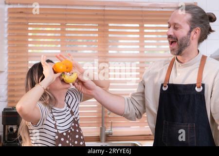 Padre e madre nella cucina della casa si divertono a preparare la cena insieme, aspettando il ritorno del giovane da Foto Stock