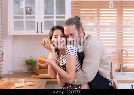 Padre e madre nella cucina della casa si divertono a preparare la cena insieme, aspettando il ritorno del giovane da Foto Stock