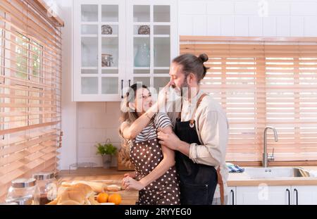 Padre e madre nella cucina della casa si divertono a preparare la cena insieme, aspettando il ritorno del giovane da Foto Stock