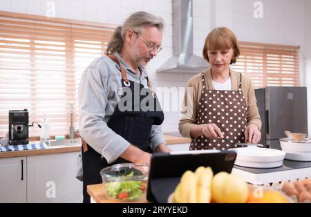 I nonni si stanno divertendo in cucina a preparare la cena per la loro figlia e i loro nipoti. Anteprima della cottura exa Foto Stock