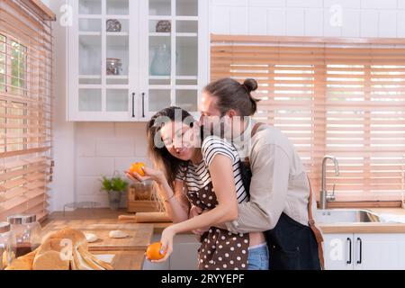 Padre e madre nella cucina della casa si divertono a preparare la cena insieme, aspettando il ritorno del giovane da Foto Stock