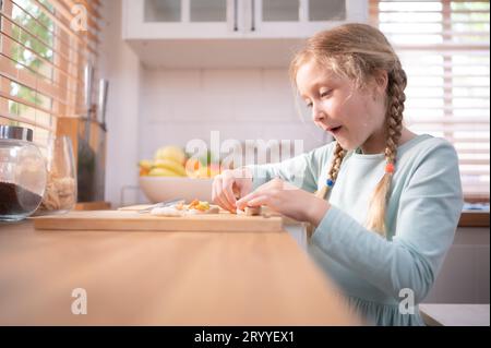 Nipote di nonni in una cucina piena di luce naturale, aiuta a cucinare la cena per la giornata per la famiglia. Foto Stock