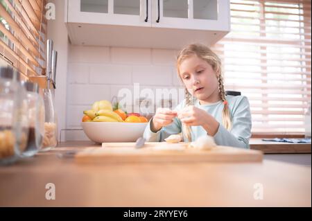 Nipote di nonni in una cucina piena di luce naturale, aiuta a cucinare la cena per la giornata per la famiglia. Foto Stock