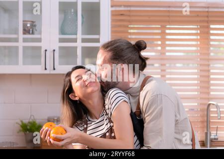 Padre e madre nella cucina della casa si divertono a preparare la cena insieme, aspettando il ritorno del giovane da Foto Stock