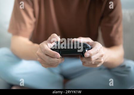 Console video con controller di gioco giovane asiatico playingÂ hobby giocoso Video online divertimento eSport Cyber Games Int Foto Stock