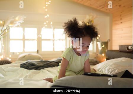 Una bambina giovane, luminosa e carina, con il suo fidato tablet che la rende felice e gioiosa. Foto Stock