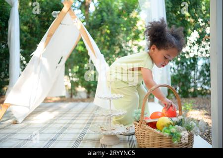 Una bambina luminosa e carina che gioca nel giardino della casa. Foto Stock