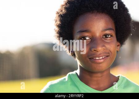 Ritratto di uno studente afroamericano sorridente nel soleggiato campo sportivo delle scuole elementari, spazio fotocopie Foto Stock