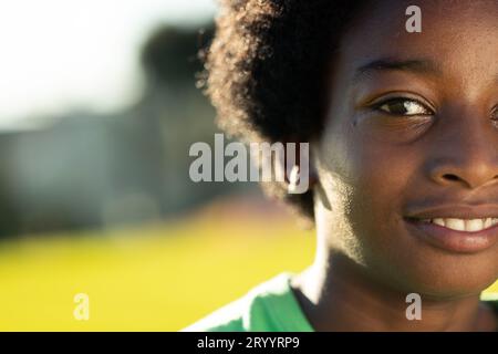 Ritratto di uno studente afroamericano sorridente nel soleggiato campo sportivo delle scuole elementari, spazio fotocopie Foto Stock