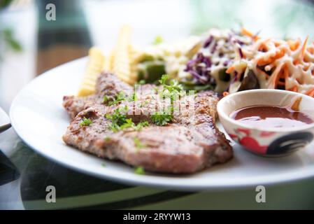 Tritare la carne di maiale bistecca con insalata e salsa di salsa nel piatto. Il cibo e il concetto di vegetali. Ristorante e il tema del menu. Foto Stock