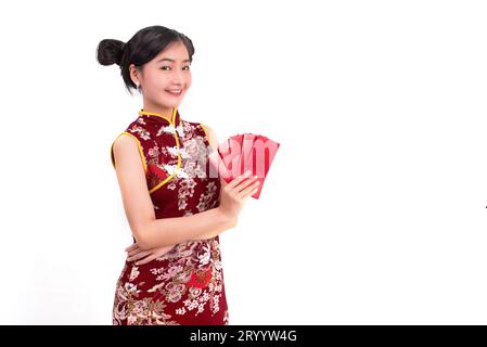 Giovane donna di bellezza asiatica che indossa cheongsam e tiene in mano il pacchetto di gesti di denaro nell'evento cinese del Capodanno su Foto Stock