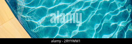 Acqua della piscina astratta. I caustici sul fondo della piscina si riversano e scorrono con onde che fanno da sfondo alla piscina blu Foto Stock