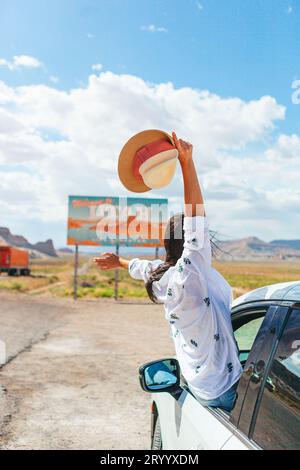 Bella donna nel suo viaggio vicino alla macchina. Benvenuto all'insegna dello Utah Road. Un grande cartello di benvenuto ti dà il benvenuto a Monument Valley, Utah Foto Stock