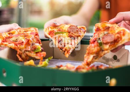 La gente mani prendendo fette di pizza Margherita. Pizza Margherita e le mani vicino fino su sfondo nero. Foto Stock